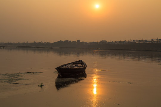 Solitary wooden boat at sunset in the water of river Damodar, Durgapur Barrage, West Bengal, India.