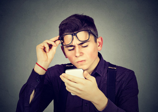 man with glasses having trouble seeing cell phone vision problems