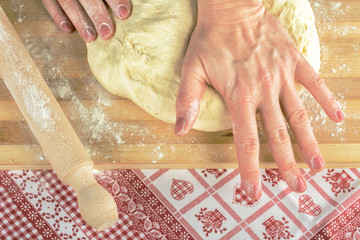 Hardworking female hands knead dough with love