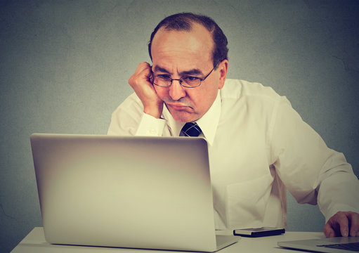 Annoyed bored middle aged man learning how to use computer