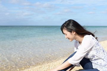 Fototapeta na wymiar 南国沖縄の美しいビーチで寛ぐ女性