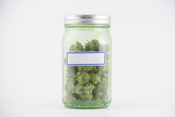 Detail of cannabis buds on green glass jar isolated on white