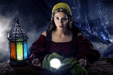 Female fortune teller doing a psychic reading with a cystal ball predicting fate or destiny and the...