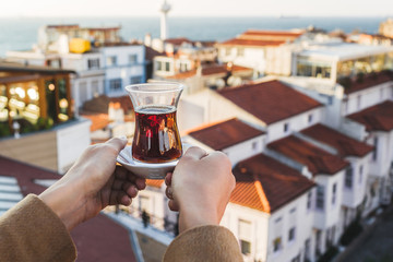 Hand holding a cup of traditional Turkish tea illuminated and tr