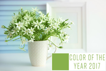 Trendy color concept. Beautiful flowers in cup. Text COLOR OF THE YEAR 2017 on background