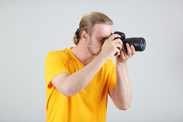 Handsome photographer with camera,on gray background