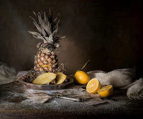 still life. pineapple, lemon, tropical juice, old silver knife on a wooden table