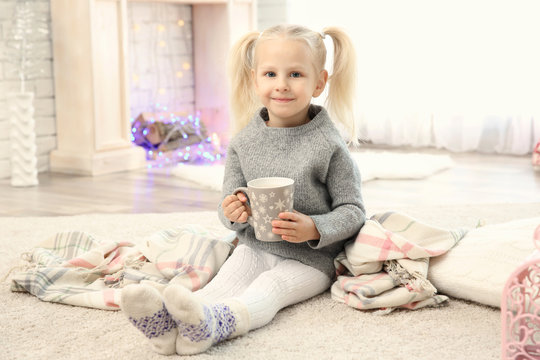 Cute little girl sitting on floor with cup of coffee