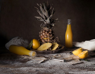 still life. pineapple, lemon, tropical juice, old silver knife on a wooden table