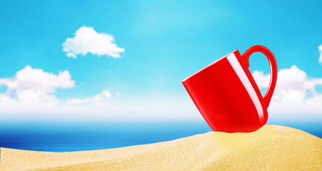 Red coffee cup on beach sand over blurry blue sky with clouds an