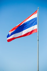 waving Thai flag of Thailand with blue sky background.
