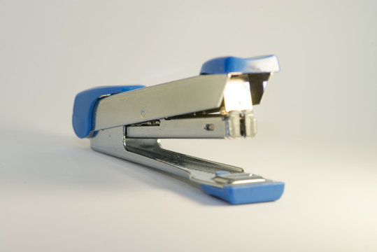 Silver and blue stapler with white background