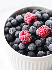 Mix of ripe berries in bowl on white background. Raspberry and blueberry in a bowl