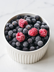 Mix of ripe berries in bowl on white background. Raspberry and blueberry in a bowl