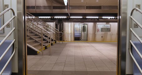 An interior view of the doors on a New York City subway car as they open at an empty platform.  	