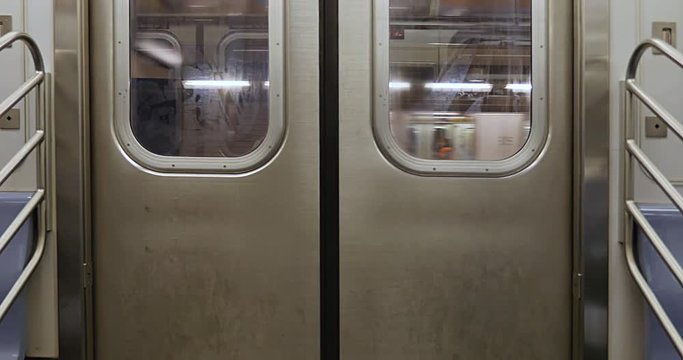 An interior shot of closed New York City subway doors as the car approaches the platform.  	