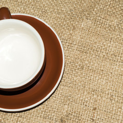 Coffee cup saucer brown close up sack background.