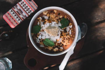 Smoothie bowl on the table with mobile phone, spoon and sun glasses