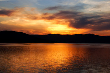 Sunset or sunrise on a pier at a mountain lake, monochrome landscape with quiet water, lake, sea