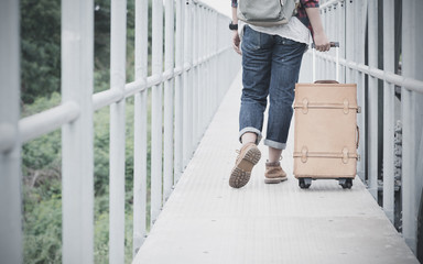 Hipster travel woman drag vintage luggage on bridge