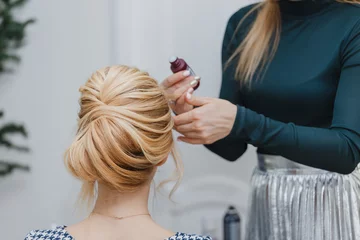 Crédence de cuisine en verre imprimé Salon de coiffure closeup of professional hairdresser hands doing beauty hairstyle a-la french twist