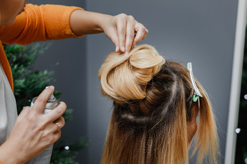 Fototapeta premium Master stylist makes the bride wedding hairstyle using spray lac