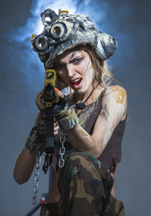 Obraz premium Young woman - soldier in a helmet, is shooting a machine gun