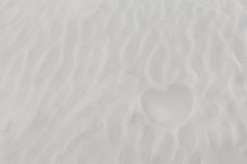 Fototapeta na wymiar Next in shape of heart on white sand