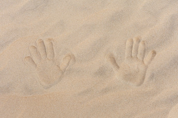 Traces of two child's hand on golden sand