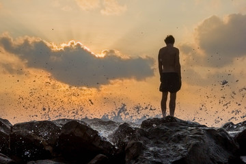 person standing on rocks seaside sunset silhouette frontback lig