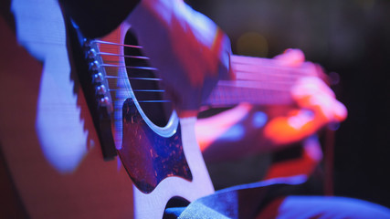 Musician in night club - guitarist plays blues acoustic guitar, extremely close up