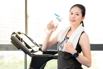 Beautiful asian woman rest holding water bottle after treadmill