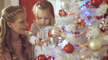 Fototapeta na wymiar Mother with adorable baby decorate a Christmas tree at home