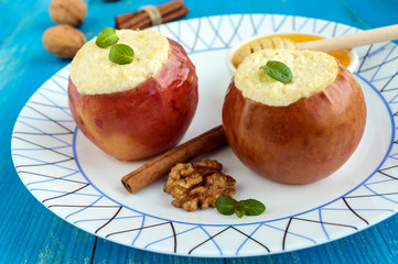 Baked apple stuffed with cottage cheese, cinnamon, walnuts with honey and mint on a blue wooden background. Close-up.