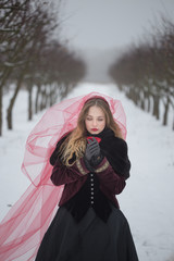 Fototapeta na wymiar girl in a red veil on the snow in the winter