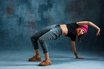 Young girl break dancing on wall background.