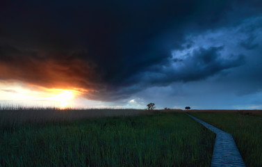 stormy sky over wooden path at sunset
