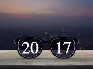2017 text with eye glasses on wooden table over blur aerial view of cityscape on warm light sundown, Business success concept