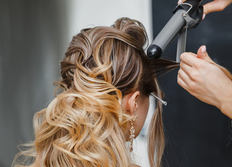 Closeup hairdresser coiffeur makes hairstyle.
