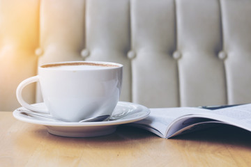 cup of latte or cappuccino coffee with a book in coffee shop with vintage retro filter effect