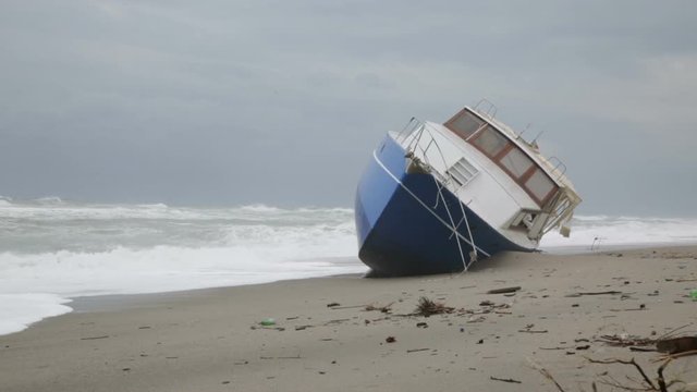 Nave arenata sulla spiaggia con le onde che si infrangono su di essa