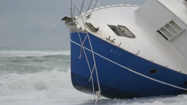 Nave arenata sulla spiaggia con le onde che si infrangono su di essa