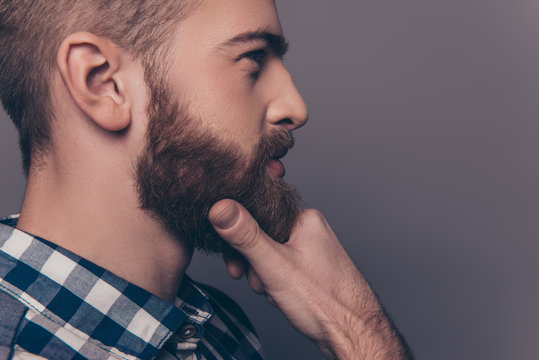 Side view portrait of thinking stylish young man touch his beard