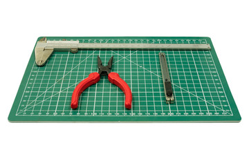 Red pliers, cutter and vernier caliper on the green cutting plate