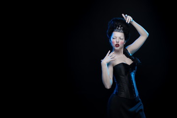 brunette woman with high hair, a tiara and a corset in old style on a black background
