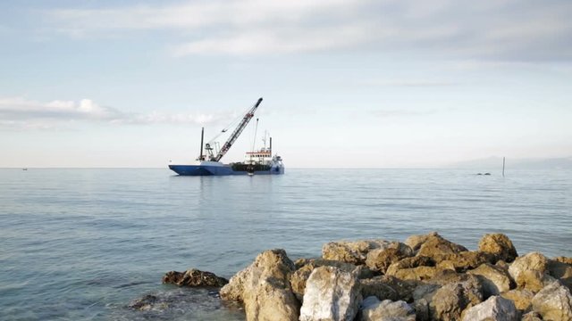 Nave Pontone sta creando una barriera di sassi di fronte la costa 