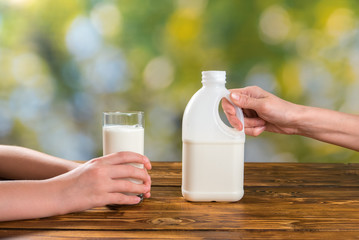 Mother hands with botlle of milk and child's holding glass