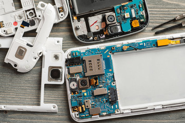 Disassembled parts of cell phone on wooden table