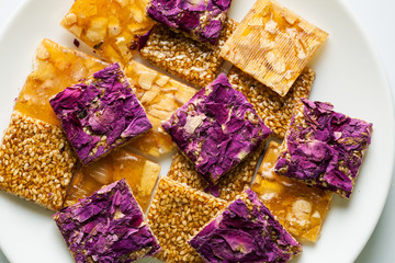 Fototapeta na wymiar Pile of oriental sweets with nuts, seeds and rose petals in a white plate