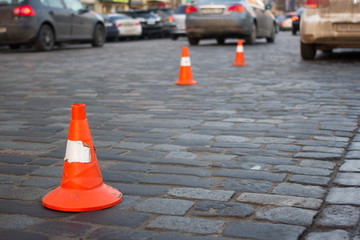 Traffic cone stay on paving stone  street. Limit for parking